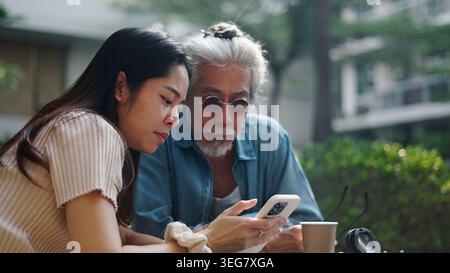 Les gens qui utilisent leur smartphone ensemble, les générations précédentes apprennent de nouvelles technologies Banque D'Images