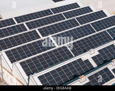 Les panneaux solaires sont installés sur les toits d'un site d'énergie solaire produisant de l'électricité renouvelable pendant les heures de lumière du jour sur un bâtiment industriel. Banque D'Images