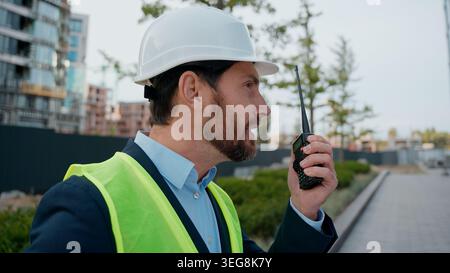 Caucasien homme en colère entrepreneur en ville criant talkie walkie problème de construction Mad négatif agressif architecte ingénieur réparateur criant urbain Banque D'Images