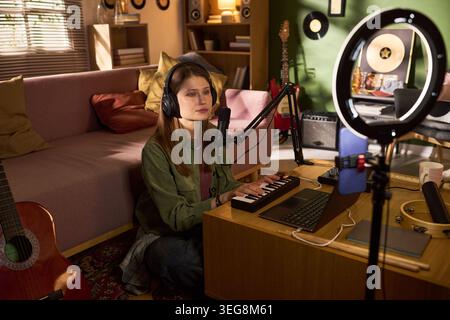 Jeune femme enregistrant du contenu musical pour Home Studio streaming Banque D'Images