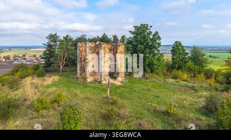 Vue aérienne des ruines de la chapelle de l'exaltation de la Sainte Croix à Bristev. Entourés d'herbe et d'arbres, les restes se dressent sur une colline avec un paysage en arrière-plan. Banque D'Images