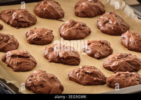 Biscuits au chocolat frais faits maison sur du papier cuisson, juste cuit sur un plateau pour le dessert, la cuisson et le contenu de la recette Banque D'Images
