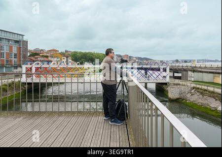 Photographe masculin capturant des paysages urbains depuis un pont dans les Asturies Banque D'Images