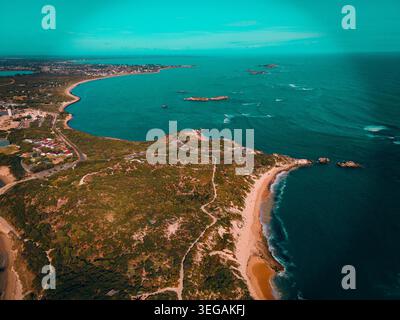 Cette superbe image aérienne met en valeur un vaste paysage côtier, avec des eaux turquoises rencontrant des rivages rocheux et des plages de sable. Le vert luxuriant Banque D'Images