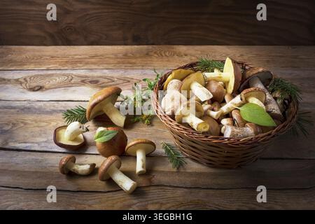 Panier avec des champignons forestiers sauvages sur le fond en bois rustique. Champignons crus frais dans le panier Banque D'Images