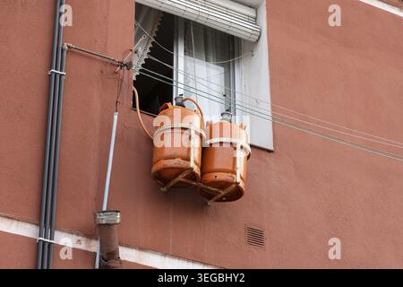 Ancienne maison espagnole avec deux bouteilles de gaz butane orange suspendues à l'extérieur d'une fenêtre, fournissant de l'énergie pour le chauffage et la cuisine Banque D'Images
