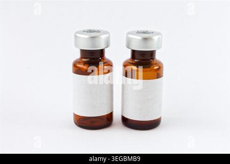 Paire de flacons médicaux en verre ambré, côte à côte sur blanc. Étiquettes vierges pour la marque pharmaceutique, les maquettes de vaccins et les soins de santé. Banque D'Images