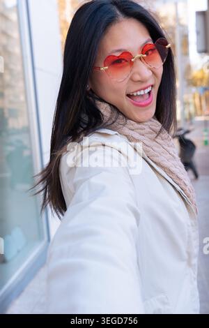 Portrait vertical femme asiatique heureuse prenant selfie sur la rue de la ville Banque D'Images