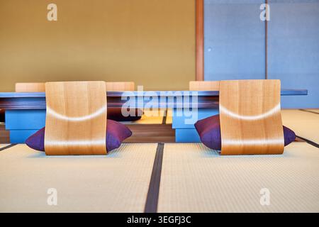 Intérieur japonais moderne avec un sol en tatami traditionnel et des chaises contemporaines en bois courbé conçues pour la position seiza Banque D'Images