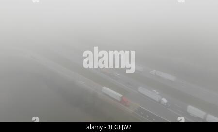 Vue aérienne de voitures circulant sur une autoroute de campagne dans un brouillard épais Banque D'Images
