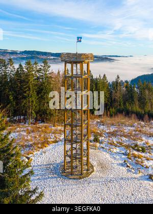 La tour d'observation de Svetly Vrch à Albrechtice se dresse au milieu du paysage hivernal. La neige recouvre le sol et des arbres entourent ce site populaire. Les gens apprécient la vue depuis la tour. Banque D'Images