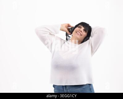 Femme mature joyeuse écoutant de la musique tenant smartphone Banque D'Images