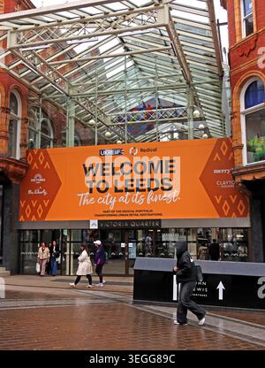 Entrée de Leeds dans le quartier Victoria avec panneau orange Bienvenue à Leeds, acheteurs et verrière d'arcade en verre Banque D'Images
