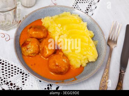 assiette ronde blanche avec boulettes de viande saupoudrées d'aneth haché dans une sauce tomate avec purée de pommes de terre Banque D'Images