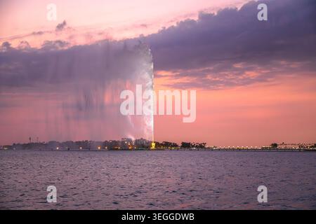 La fontaine du roi Fahd, la plus haute fontaine du monde, pulvérise de l'eau dans le front de mer de Djeddah, en Arabie Saoudite, au coucher du soleil, avec un ciel nuageux spectaculaire et Banque D'Images