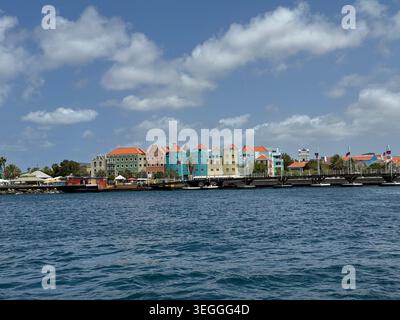 Vue panoramique sur les célèbres bâtiments colorés Handelskade Waterfront à travers l'eau bleue de la baie à Willemstad, Curaçao. Banque D'Images