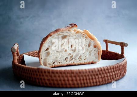 Demi-pain de levain artisanal fraîchement cuit. La coupe transversale révèle une miette ouverte poreuse bien fermentée et une croûte dorée croustillante. Placé sur Banque D'Images