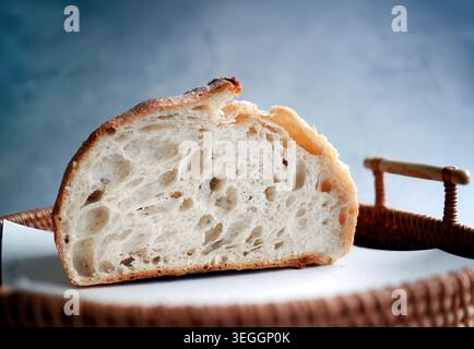 Demi-pain de levain artisanal fraîchement cuit. La coupe transversale révèle une miette ouverte poreuse bien fermentée et une croûte dorée croustillante. Placé sur Banque D'Images