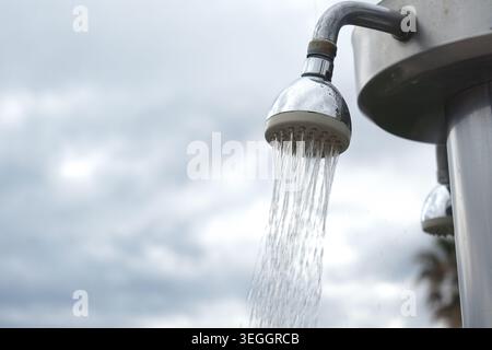L'eau coule d'une pomme de douche dans un cadre extérieur Banque D'Images