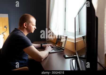 Homme tapant sur un ordinateur portable, se concentrant sur le travail à un bureau à l'intérieur Banque D'Images