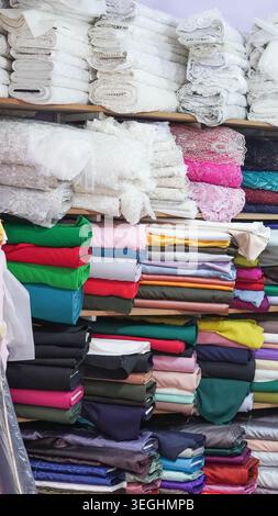 Étagères empilées avec des boulons de tissu coloré et des rouleaux de dentelle dans un magasin de textile Banque D'Images