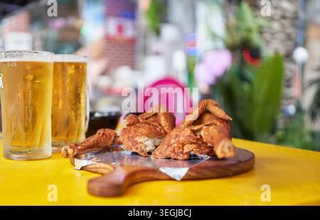 Dégustez un authentique Chimaek coréen accompagné d'un poulet entier frit croustillant et d'une bière pression froide sur une table jaune éclatante, capturant la soirée parfaite. Banque D'Images