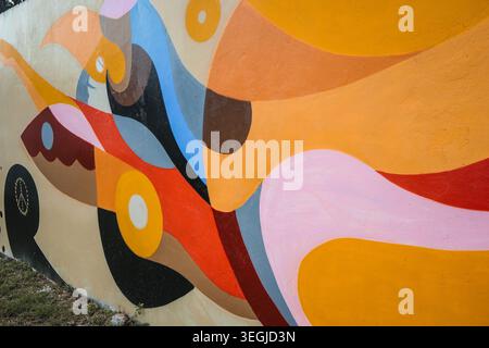 Montego Bay, Jamaïque — 28 novembre 2025 : murale abstraite vibrante d'art de rue avec des formes géométriques et des couleurs chaudes sur un mur extérieur en béton. Banque D'Images