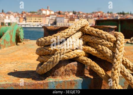 Corde épaisse enroulée autour d'une borne rouillée sur un quai à Rovinj, Croatie. Banque D'Images