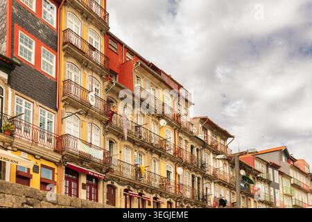 Vue en bas angle regardant les façades colorées vibrantes du quartier Ribeira de Porto, montrant des balcons en fer ornés avec buanderie suspendue et Banque D'Images