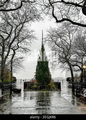 Arbre à feuilles persistantes et mât de drapeau de Noël au bout de Montague Street sur la Brooklyn Heights Promenade par un jour d'hiver pluvieux Banque D'Images