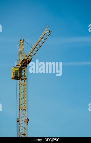 Grue à tour de construction jaune contre le ciel bleu clair, vue d'angle bas. Banque D'Images