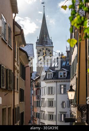 Vue à travers une ruelle étroite vers la grande horloge de la tour de l'église de Pierre à Zurich Banque D'Images