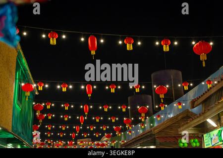 Global Village, Dubaï, Émirats arabes Unis- 23 novembre 2025 : lanternes traditionnelles chinoises rouges illuminées la nuit, suspendues au-dessus des bâtiments du marché à Global Village Banque D'Images