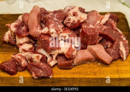 Morceaux d'agneau fraîchement hachés sur une planche de bois préparée pour la cuisine traditionnelle ouzbek plov, ingrédients rustiques de la cuisine d'Asie centrale dans la cuisine à la maison. Banque D'Images