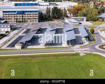 Il s'agit d'une vue d'en haut montrant une aire de stationnement couverte de panneaux solaires et de voitures stationnées. Les bâtiments à proximité sont visibles. Banque D'Images