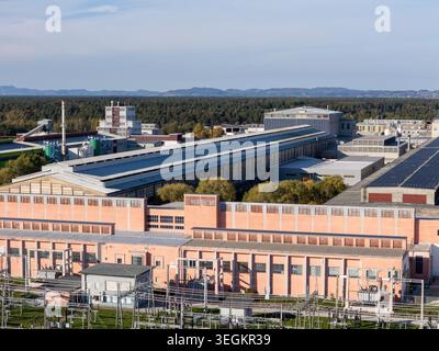 La vue aérienne montre une zone industrielle avec des bâtiments, des panneaux solaires et des lignes électriques sous un ciel dégagé pendant la journée. Banque D'Images