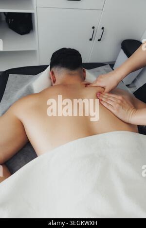 L'homme est allongé en arrière, détendu, recevant un massage des épaules Banque D'Images