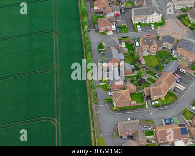 Vue aérienne par drone d'un lotissement britannique à côté de champs de culture verdoyants à Selby North Yorkshire UK montrant des rues de banlieue, des terres agricoles et des pistes de tracteurs Banque D'Images