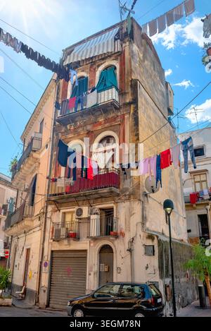 Séchage des vêtements accrochés sur les cordes à linge entre les bâtiments résidentiels dans la rue au quartier historique de Catane. Sicile, Italie Banque D'Images