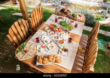 Petit-déjeuner méditerranéen copieux servi en plein air, petit-déjeuner turc traditionnel abondant avec du pain frais, du fromage, des olives, des œufs et des ingrédients de saison Banque D'Images