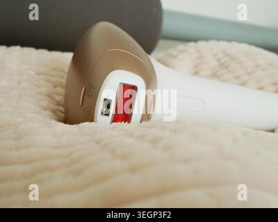 Appareil d'épilation laser à lumière pulsée en or blanc reposant sur un oreiller de fourrure beige confortable Home Beauty Aesthetic Product Shot, Smooth Skin Care Technology close-up. A Banque D'Images