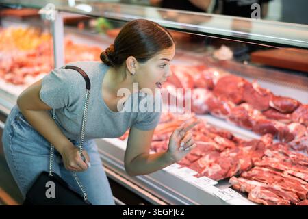 Jeune femme acheteur choisit le bœuf dans la boucherie Banque D'Images