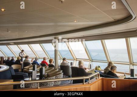 Serveur servant les invités pendant qu'ils se détendent et admirent la vue panoramique sur l'océan depuis le salon d'observation d'un bateau de croisière (2026) Banque D'Images