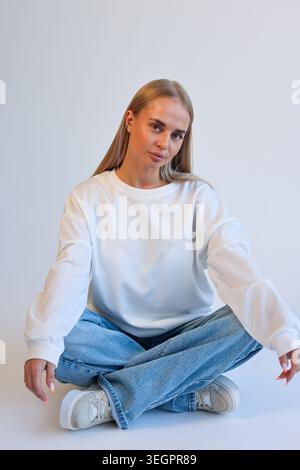 Jeune femme détendue souriant naturellement. Jeune femme confortable assise avec une présence amicale Banque D'Images