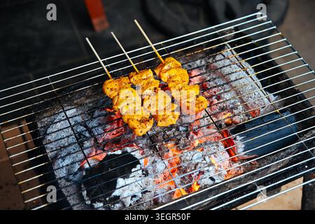 Les brochettes de viande Thit Nuong vietnamiennes traditionnelles sont grillées sur du charbon de bois brûlant chaud dans un étal de marché de nourriture de rue dans la ville antique de Hoi an Banque D'Images
