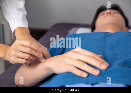 Un médecin place doucement un bandage sur le bras d'un patient dans un cabinet médical. Banque D'Images