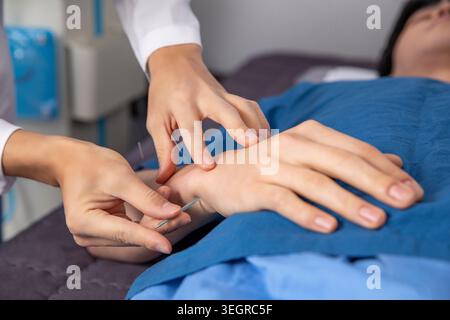 Une femme est traitée par acupuncture au poignet par un professionnel de la santé dans un cadre médical. Banque D'Images