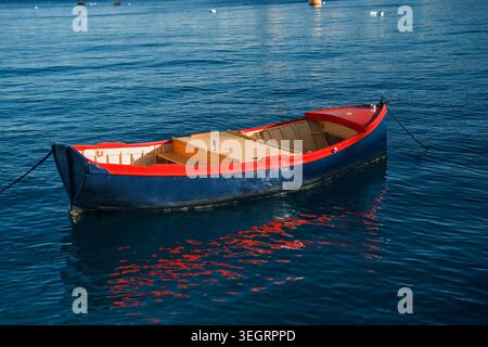 Petit bateau de pêche amarré flottant sur la mer bleue calme Banque D'Images