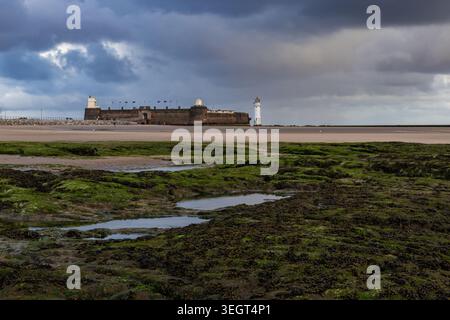 Fort Perch Rock et le phare de Perch Rock vus à travers des rochers couverts d'algues et des bassins de marée à New Brighton Banque D'Images