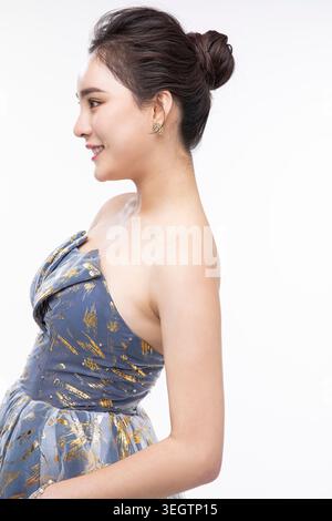 Une jeune femme dans une robe formelle se tient dans un studio, souriant à la caméra. Banque D'Images